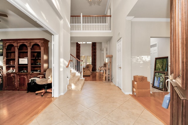 entryway featuring light wood-type flooring, ornamental molding, and a high ceiling