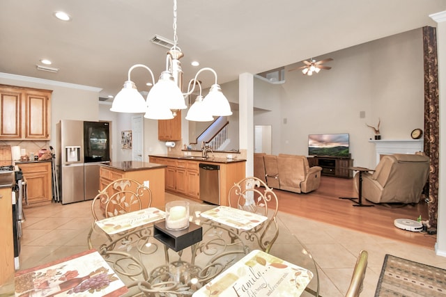 tiled dining room with ceiling fan with notable chandelier, ornamental molding, and sink