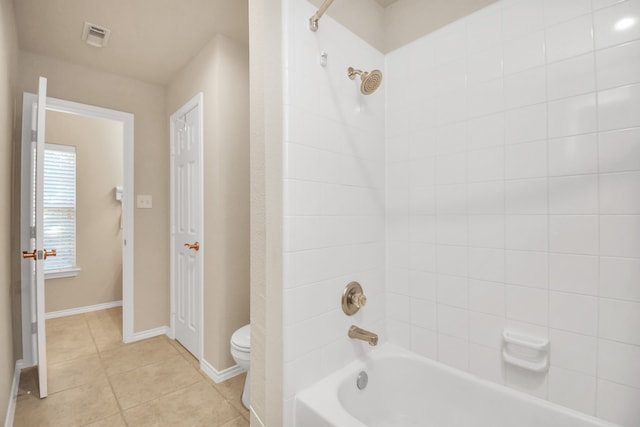 bathroom with tile patterned flooring, toilet, and tiled shower / bath