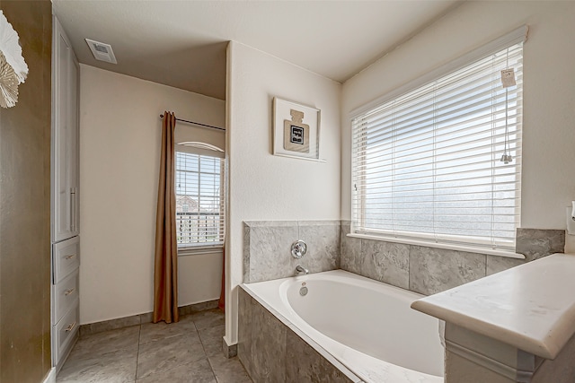 bathroom with tile patterned floors and a relaxing tiled tub