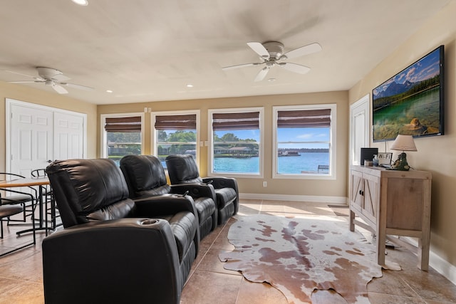 tiled living room featuring ceiling fan and a water view