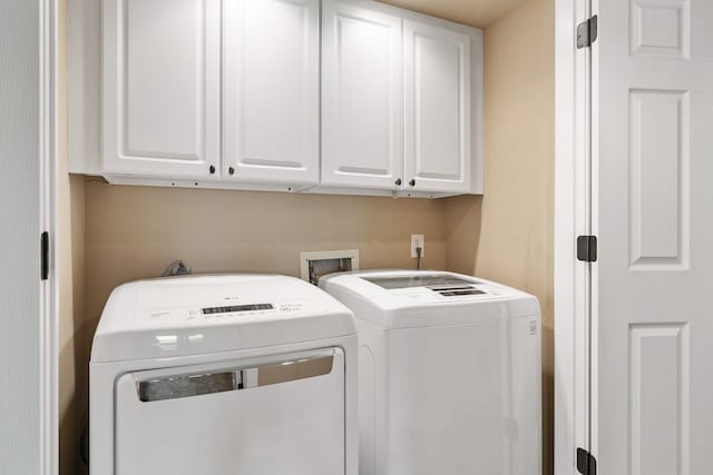 clothes washing area with cabinets and washer and dryer