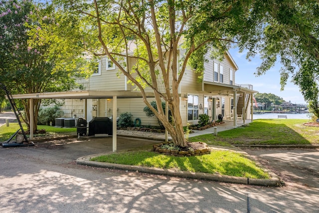 view of front facade featuring a water view, a front lawn, and central AC unit