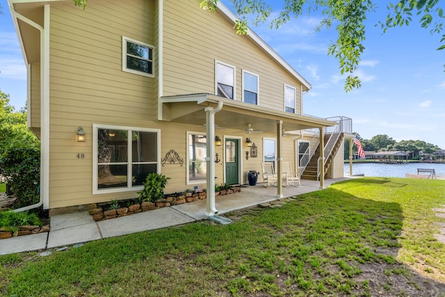 rear view of house featuring a yard, a water view, ceiling fan, and a patio area