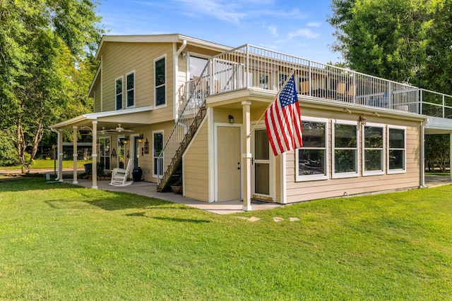 back of house with ceiling fan, a balcony, and a yard