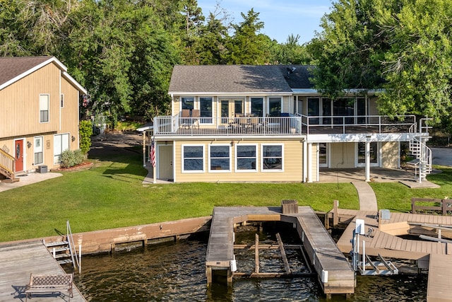 back of house with a sunroom, a patio area, a deck with water view, and a lawn