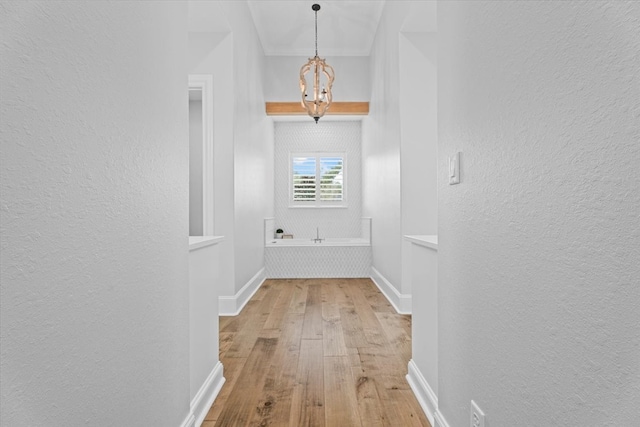 hallway featuring wood-type flooring and an inviting chandelier