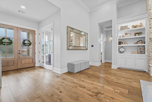 foyer with french doors, light hardwood / wood-style floors, and crown molding