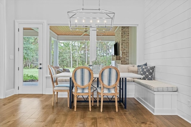 dining space featuring wood-type flooring, breakfast area, an inviting chandelier, and wood walls