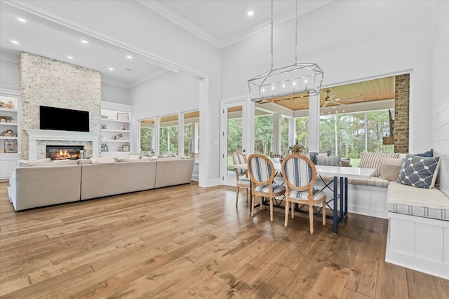 living room featuring light hardwood / wood-style floors, crown molding, a towering ceiling, and a fireplace