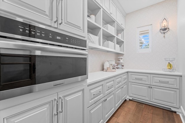 kitchen with oven, white cabinetry, and dark wood-type flooring