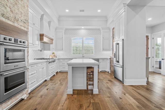 kitchen with a wealth of natural light, white cabinetry, a kitchen island, and appliances with stainless steel finishes