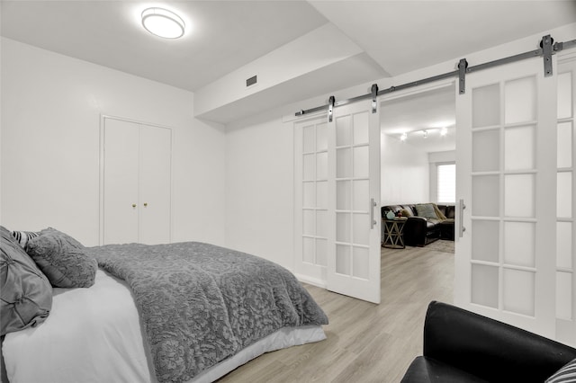 bedroom with light wood-type flooring, a closet, and a barn door