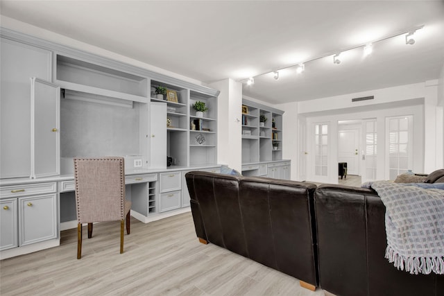 living room with light hardwood / wood-style flooring, built in desk, and track lighting