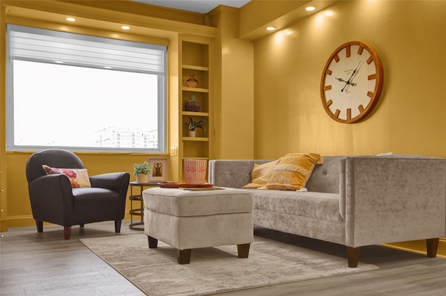 sitting room featuring built in shelves, a wealth of natural light, and hardwood / wood-style floors