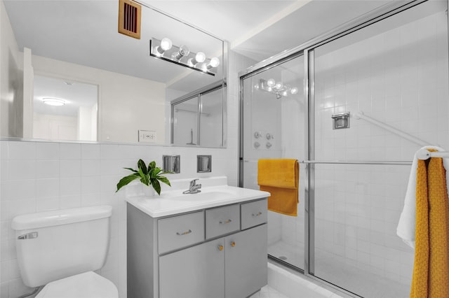 bathroom featuring vanity, a shower with shower door, and tile walls