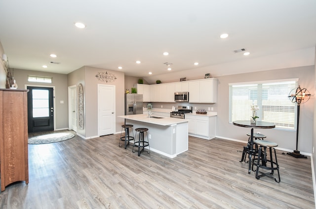 kitchen featuring a wealth of natural light, an island with sink, appliances with stainless steel finishes, and light hardwood / wood-style flooring