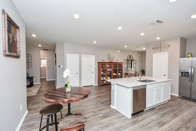 kitchen with sink, stainless steel appliances, light hardwood / wood-style flooring, a center island with sink, and white cabinets