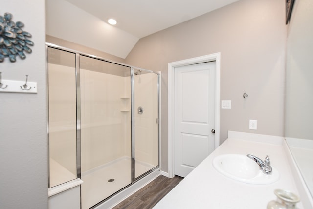 bathroom with hardwood / wood-style floors, vanity, a shower with shower door, and vaulted ceiling