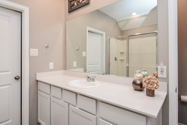 bathroom featuring vanity, walk in shower, and lofted ceiling