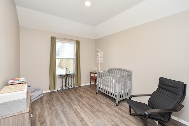 bedroom with a crib and light wood-type flooring