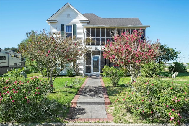 view of front of home with a front yard and a sunroom