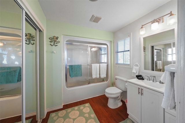 full bathroom with shower / bath combination with glass door, hardwood / wood-style floors, vanity, and toilet