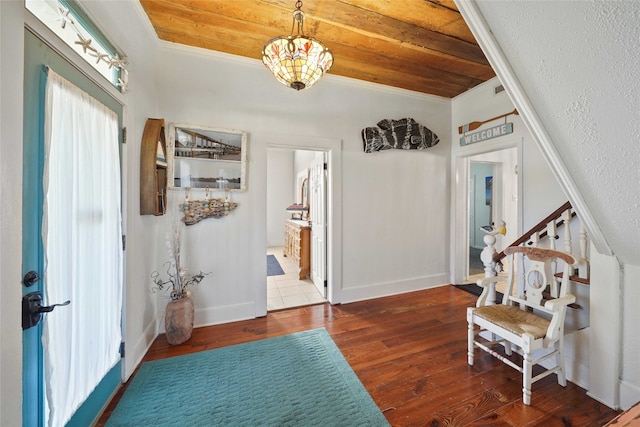 foyer entrance with wooden ceiling, crown molding, dark wood-type flooring, and an inviting chandelier