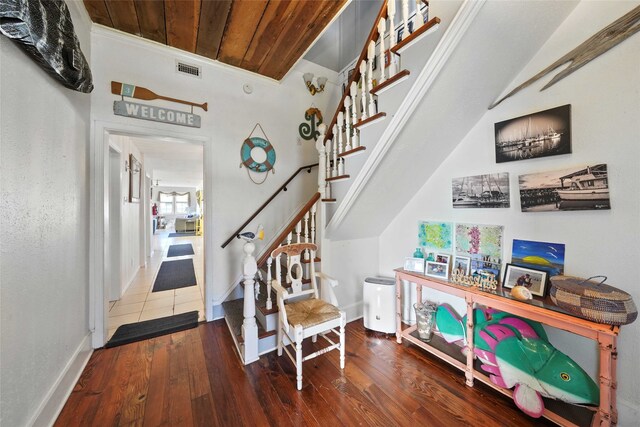 stairway featuring wood-type flooring, ornamental molding, and wood ceiling