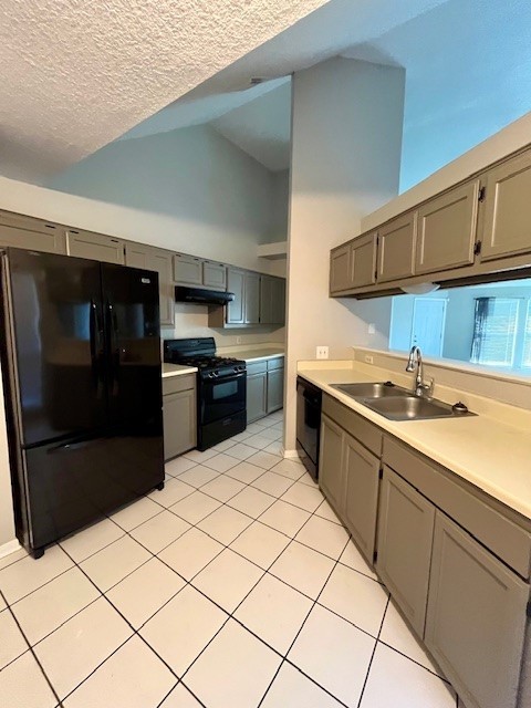 kitchen with a textured ceiling, vaulted ceiling, sink, black appliances, and light tile patterned floors