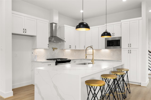 kitchen with white cabinetry, built in microwave, sink, wall chimney range hood, and stainless steel range with gas cooktop