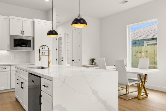 kitchen with decorative light fixtures, sink, white cabinetry, and stainless steel appliances