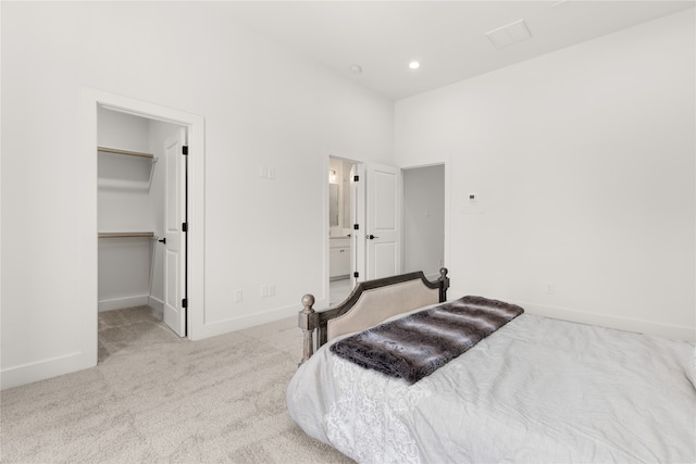 carpeted bedroom with ensuite bath, a spacious closet, and a closet