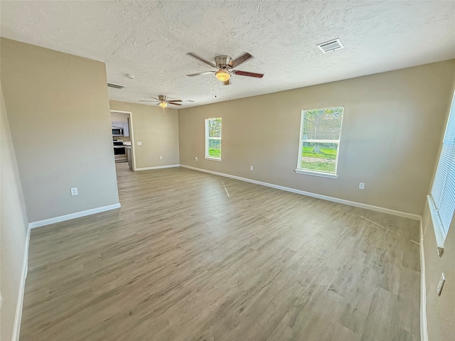 empty room featuring a textured ceiling, light wood-type flooring, and ceiling fan