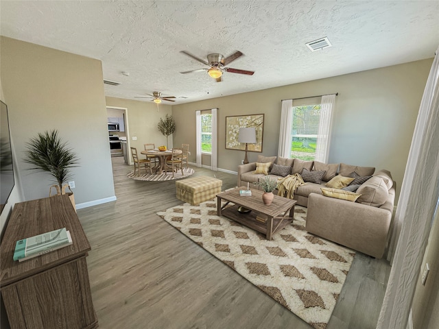 living room featuring ceiling fan, hardwood / wood-style floors, a healthy amount of sunlight, and a textured ceiling