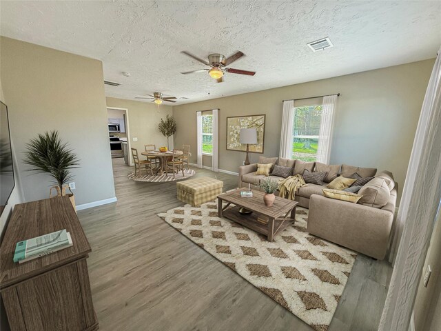 304 E Caroline St, Trinity, TX 75862 - living room featuring ceiling fan, hardwood / wood-style floors, a healthy amount of sunlight, and a textured ceiling