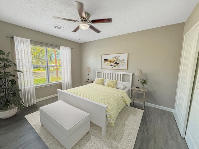 bedroom featuring a textured ceiling, dark hardwood / wood-style floors, and ceiling fan