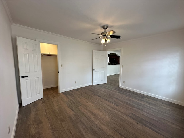 unfurnished bedroom with a spacious closet, ceiling fan, dark hardwood / wood-style flooring, a closet, and ornamental molding