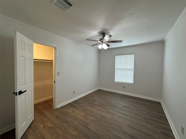 unfurnished bedroom featuring a closet, a walk in closet, dark hardwood / wood-style floors, and ceiling fan