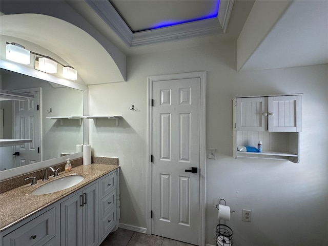 bathroom featuring tile patterned flooring, vanity, crown molding, and a tray ceiling