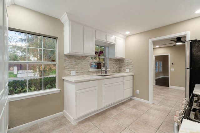 kitchen with decorative backsplash, stainless steel fridge, plenty of natural light, and white cabinetry