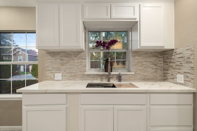 kitchen featuring backsplash, light stone countertops, sink, and white cabinets