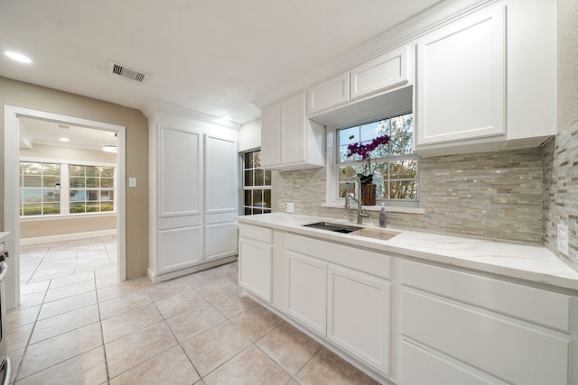 kitchen featuring white cabinetry, sink, light stone counters, backsplash, and light tile patterned floors