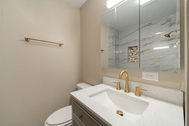 bathroom with vanity, toilet, and tiled shower