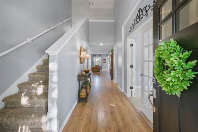 entryway with hardwood / wood-style flooring, a towering ceiling, and french doors