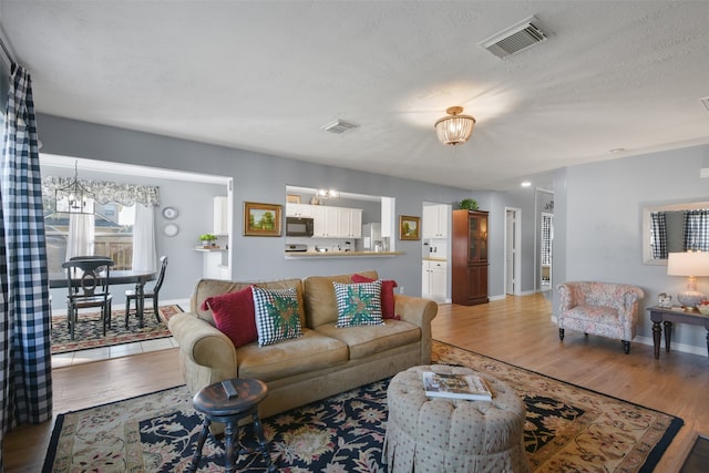 living room with wood-type flooring, a textured ceiling, and an inviting chandelier