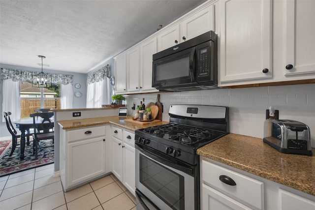 kitchen featuring light tile patterned flooring, backsplash, white cabinets, a notable chandelier, and gas stove