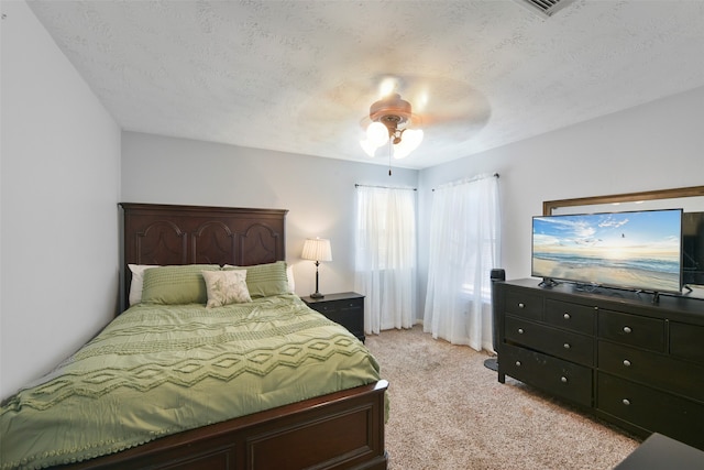 bedroom featuring ceiling fan, a textured ceiling, and light carpet