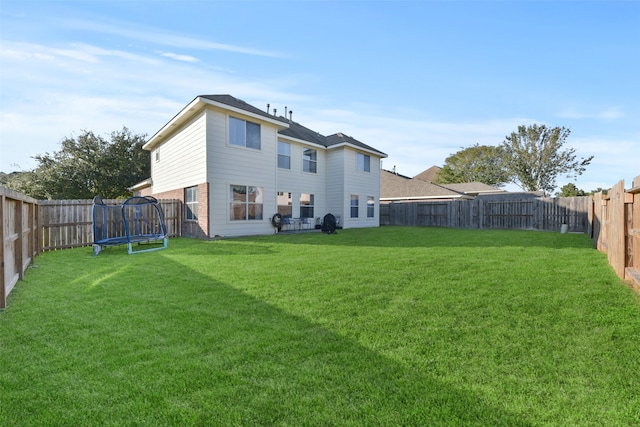 rear view of house with a lawn and a trampoline