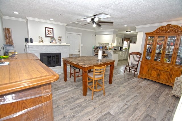 dining space featuring ceiling fan, ornamental molding, a textured ceiling, and light wood-type flooring